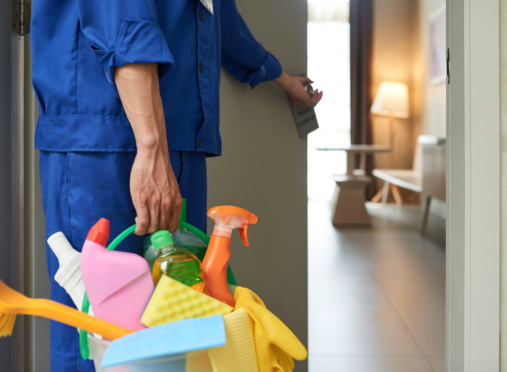 Professional cleaner with bucket of detergents opening room