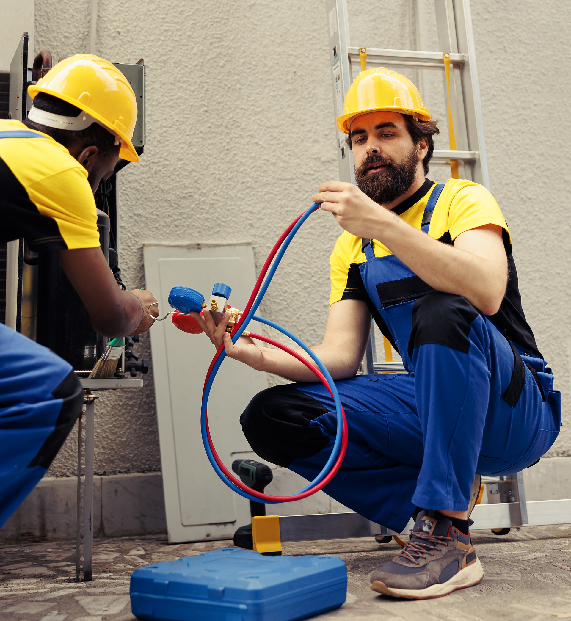 Seasoned mechanic using soft dusting brush to sweep away built up layer of dirt and debris from hvac system coil while adept repairman refills air conditioner cooling system refrigerant tank